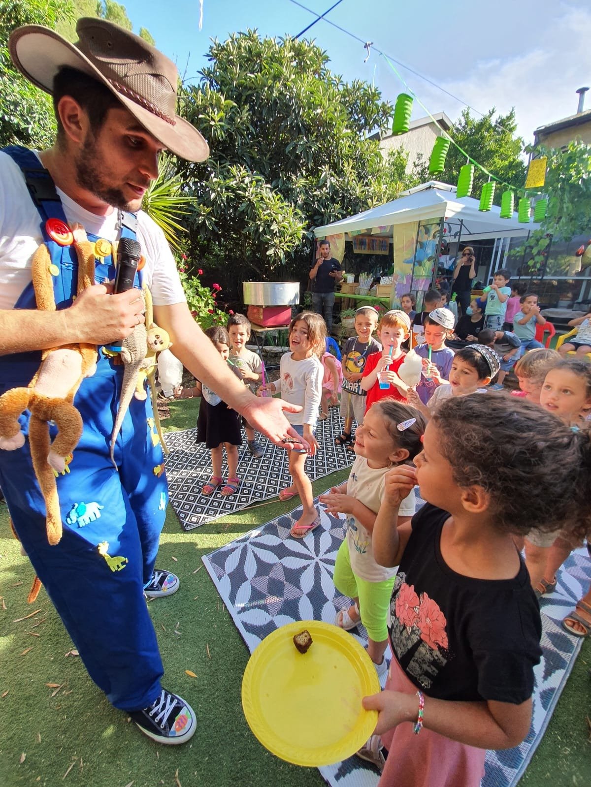 קבוצת ילדים נהנית בהפעלה עם חיות באירוע בחצר - ימבמבם